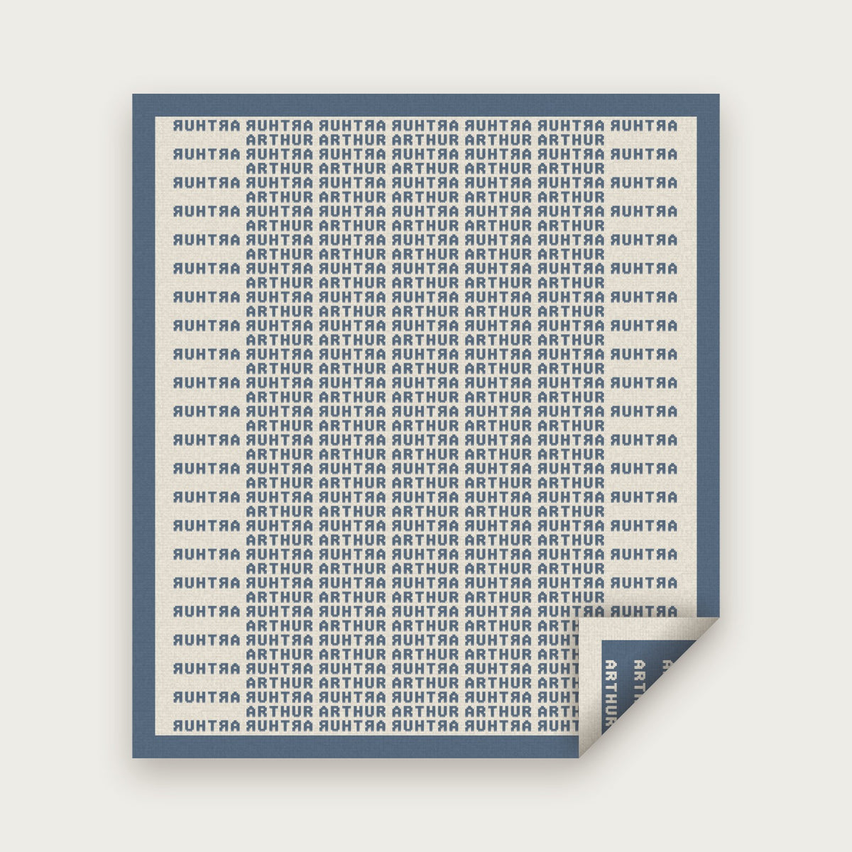 The Heir blanket in Dusk blue and bone, laid flat with one corner folded back to show the reverse