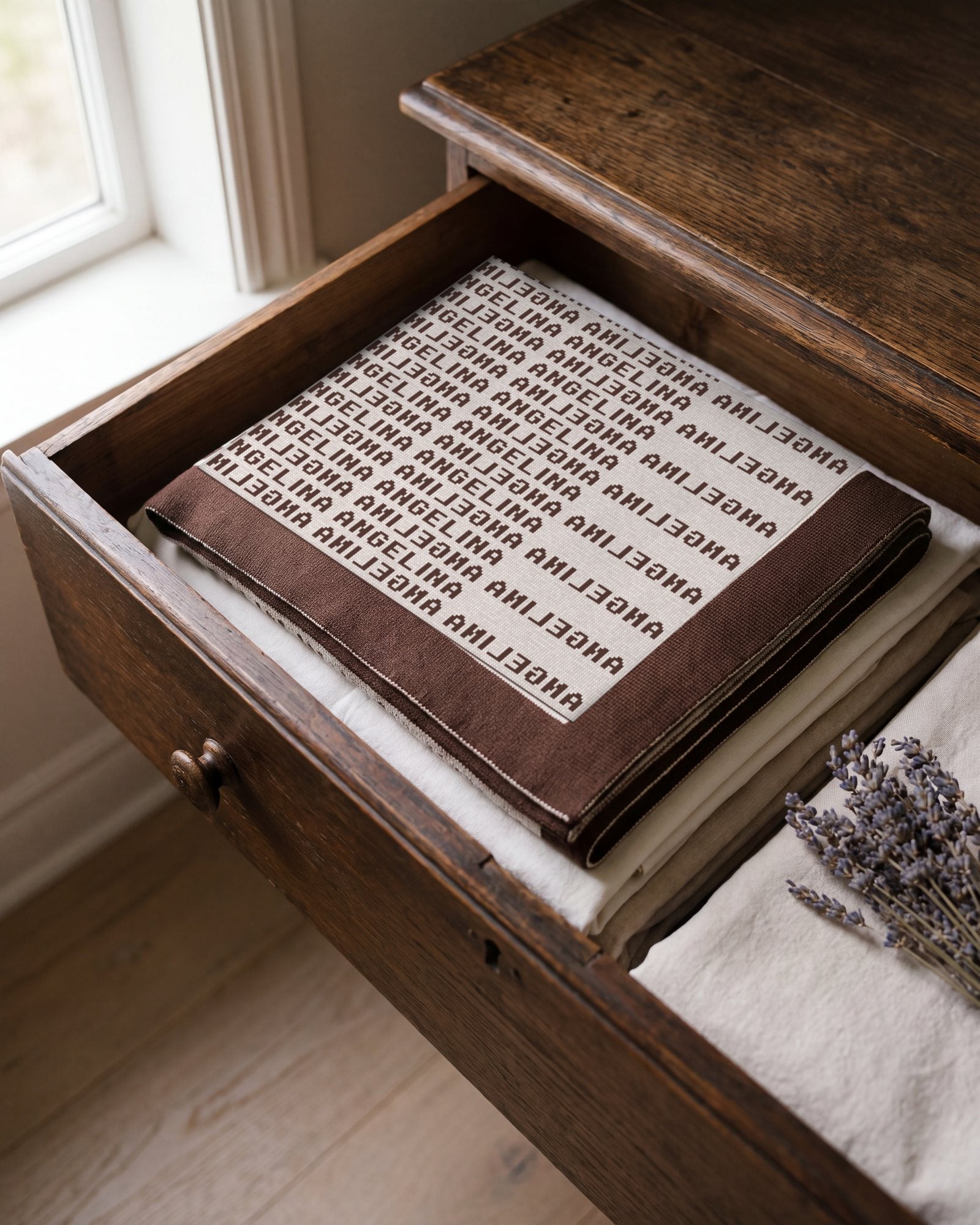 The blanket folded among plain linens in an open oak drawer, with dried lavender beside it